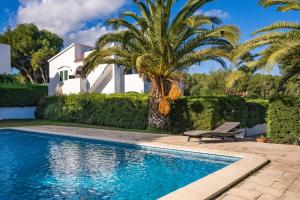 a house with a palm tree and a swimming pool at Las Violetas in Arenal d'en Castell