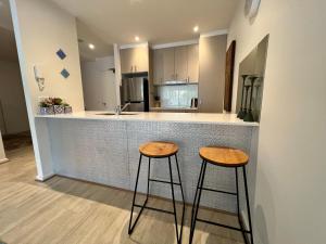 una cucina con due sgabelli di fronte a un bancone di Envy 11 Luxe 1BR Apt Braddon WiFi Netflix Wine Secure Parking Canberra a Canberra