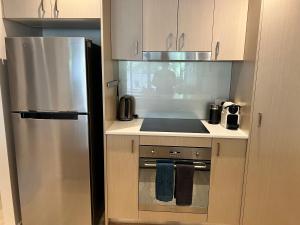 uma pequena cozinha com um frigorífico de aço inoxidável em Envy 11 Luxe 1BR Apt Braddon WiFi Netflix Wine Secure Parking Canberra em Camberra