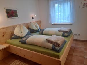 ein Holzbett mit Kissen darauf in einem Zimmer in der Unterkunft Zitas Ferienwohnung in Reisach