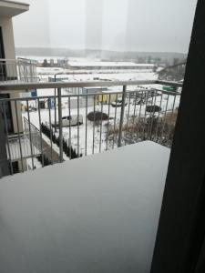 a snow covered balcony with a view of a parking lot at Apartament COSY CAVE in Uniejow