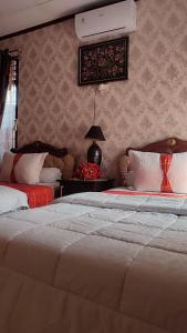 a bedroom with two beds and a table with a lamp at Cendana Homestay in Sawahlunto