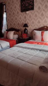 1 dormitorio con 2 camas y mesa con lámpara en Cendana Homestay, en Sawahlunto