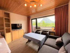 une chambre avec un canapé, une table et une fenêtre dans l'établissement Allgäu Appartementhaus Appartement ALLGÄU 14, à Pfronten