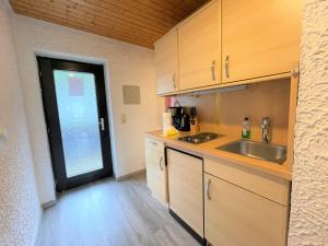 - une cuisine avec des placards en bois, un évier et une porte dans l'établissement Allgäu Appartementhaus Appartement ALLGÄU 14, à Pfronten