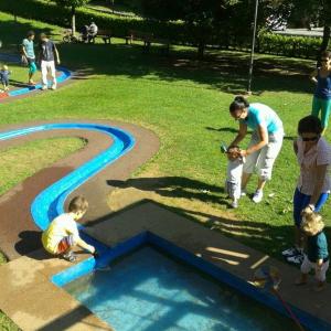 Eine Frau und zwei Kinder spielen in einem Brunnen im Park in der Unterkunft La Casa Rossa - Presolana in Castione della Presolana