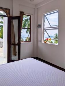 a bedroom with a bed and a window at Arazo villa in Unawatuna