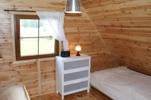 a bedroom in a log cabin with a bed and a window at Piastogród 2 in Jarosławiec