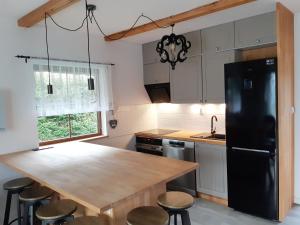 a kitchen with a wooden table and a black refrigerator at Piastogród 2 in Jarosławiec