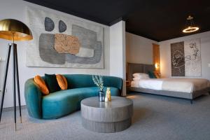 a living room with a blue couch and a bed at Das Kronberg - Adults Only Hotel in Bodenmais