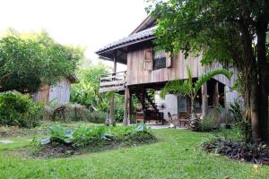 a wooden house with a porch and a yard at Lanna House Lanna Hut Chiangmai in Chiang Mai
