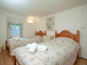 a bedroom with two beds and a mirror at Yew Tree Cottage in Branscombe
