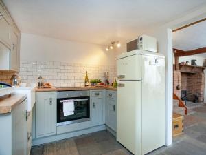 a kitchen with a white refrigerator and an oven at Yew Tree Cottage in Branscombe