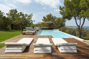 a swimming pool with chaise lounge chairs on a wooden deck at Villa Cosima - San Antonio in San Antonio