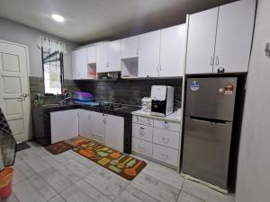 La cuisine est équipée de placards blancs et d'un réfrigérateur en acier inoxydable. dans l'établissement ANG LEE HOLIDAY HOME 1, à Semporna