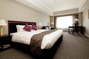 Kurashiki Royal Art Hotel في كوراشيكي: غرفة في الفندق مع سرير كبير مع وسائد أرجوانية