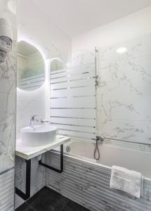 a bathroom with a tub and a sink and a bath tub at Hôtel Jardin Croisette in Cannes
