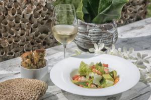 un plato de ensalada y una copa de vino blanco en W15 Escape, en Ahangama