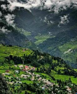 Pandava's Cafe & Stay في Chopta: اطلاله على جبل مع مدينه في وادي