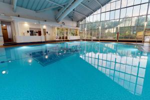 a large swimming pool with blue water in a building at Village Hotel Liverpool in Prescot