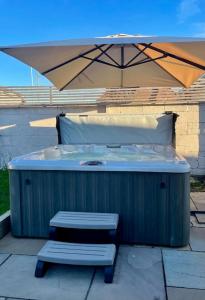 a hot tub and a bench under an umbrella at Modern, central bungalow with Luxury Hot tub in Bournemouth