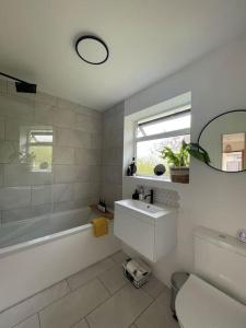 a bathroom with a tub and a sink and a mirror at Modern, central bungalow with Luxury Hot tub in Bournemouth