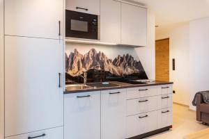 cocina con armarios blancos y microondas en Planerhof Apartment Lilie, en Funes