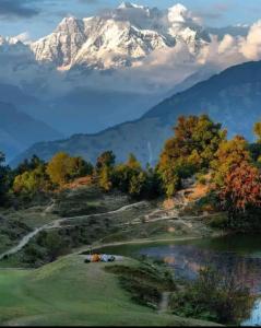 un campo de golf con una montaña en el fondo en Pandava's Cafe & Stay en Chopta