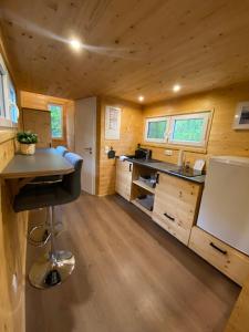 una cocina con armarios de madera y un escritorio en una casa pequeña en Tiny House Wupper im PIER9 Tiny House Hotel, en Hamm