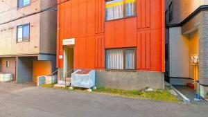 Um edifício laranja com um caixote do lixo à frente. em KIYAZA River Sapporo em Sapporo