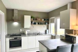a kitchen with white cabinets and a sink at Donegal Beach Cottage with Sea Views, sleeps six in Lettermacaward