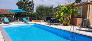 a pool with chairs and an umbrella next to a house at Villa Beausoleil in Orban