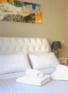 a white bed with two towels on top of it at Odyseia Apts ΙI at the Center of the City & Old Town in Chania Town