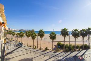 a view of a beach with palm trees and the ocean at HAPPYVILA Fisher House in Villajoyosa