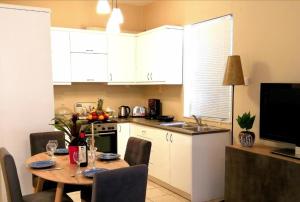 a kitchen with a table with chairs and a kitchen with white cabinets at Odyseia Apts ΙI at the Center of the City & Old Town in Chania Town +12 photos