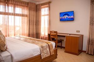 Schlafzimmer mit einem Bett und einem Schreibtisch mit einem TV in der Unterkunft Grand Winston Hotel in Nakuru