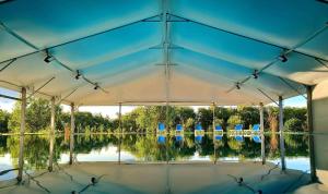 a tent with blue chairs and a lake at Gyirmót Sport & Wellness Hotel in Győr