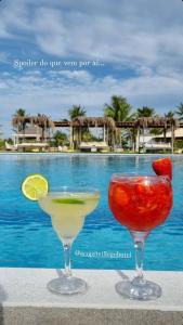 two cocktails sitting on a table next to a pool at Eco Privillege Hotel in Pacatuba