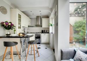 een keuken met witte kasten, een aanrecht en krukken bij Maisies Place in Brighton & Hove