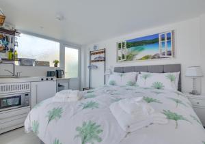 a white bedroom with a bed and a kitchen at Idrella Studio in Saltdean