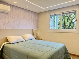 1 dormitorio con cama y ventana en Apartamento Solar do Ipê Centro 2 dorm by Achei, en Canela