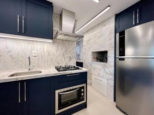cocina con armarios azules y nevera de acero inoxidable en Apartamento Solar do Ipê Centro 2 dorm by Achei, en Canela