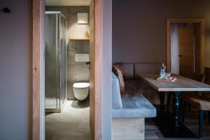 a bathroom with a toilet and a sink and a table at Panorama Hotel & Restaurant in Bettmeralp