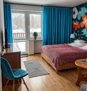 a bedroom with a bed and a desk and a chair at Willa RADosna in Karpacz