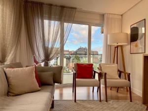格拉馬杜的住宿－Apartamentos Solar da Garibaldi CENTRO by Achei Gramado，带沙发和椅子的客厅以及大窗户。