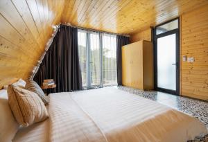 a bedroom with a large bed with a large window at Les Bois BaVi by HOLO Serviced HomeStay in Hanoi