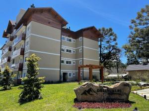 um grande edifício com uma placa em frente em Apartamentos Delle Alpi by Achei Gramado em Canela