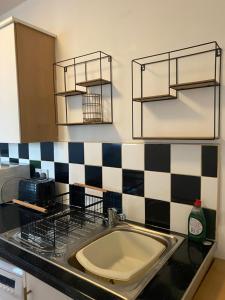a kitchen with a sink and black and white checkered wall at Nantwich House in Crewe