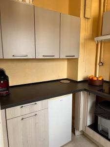 a kitchen with white cabinets and a black counter top at Le Studio: Agréable logement in Riorges