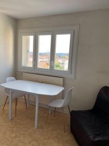 een witte tafel en stoelen in een kamer met 2 ramen bij Le Studio: Agréable logement in Riorges